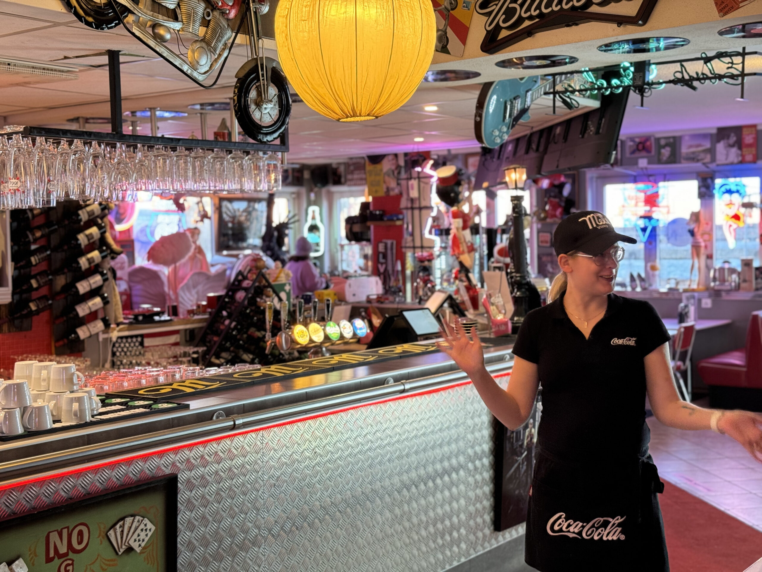 Personal bakom baren på Mel’s Diner, med glas, vinflaskor och retroinredning